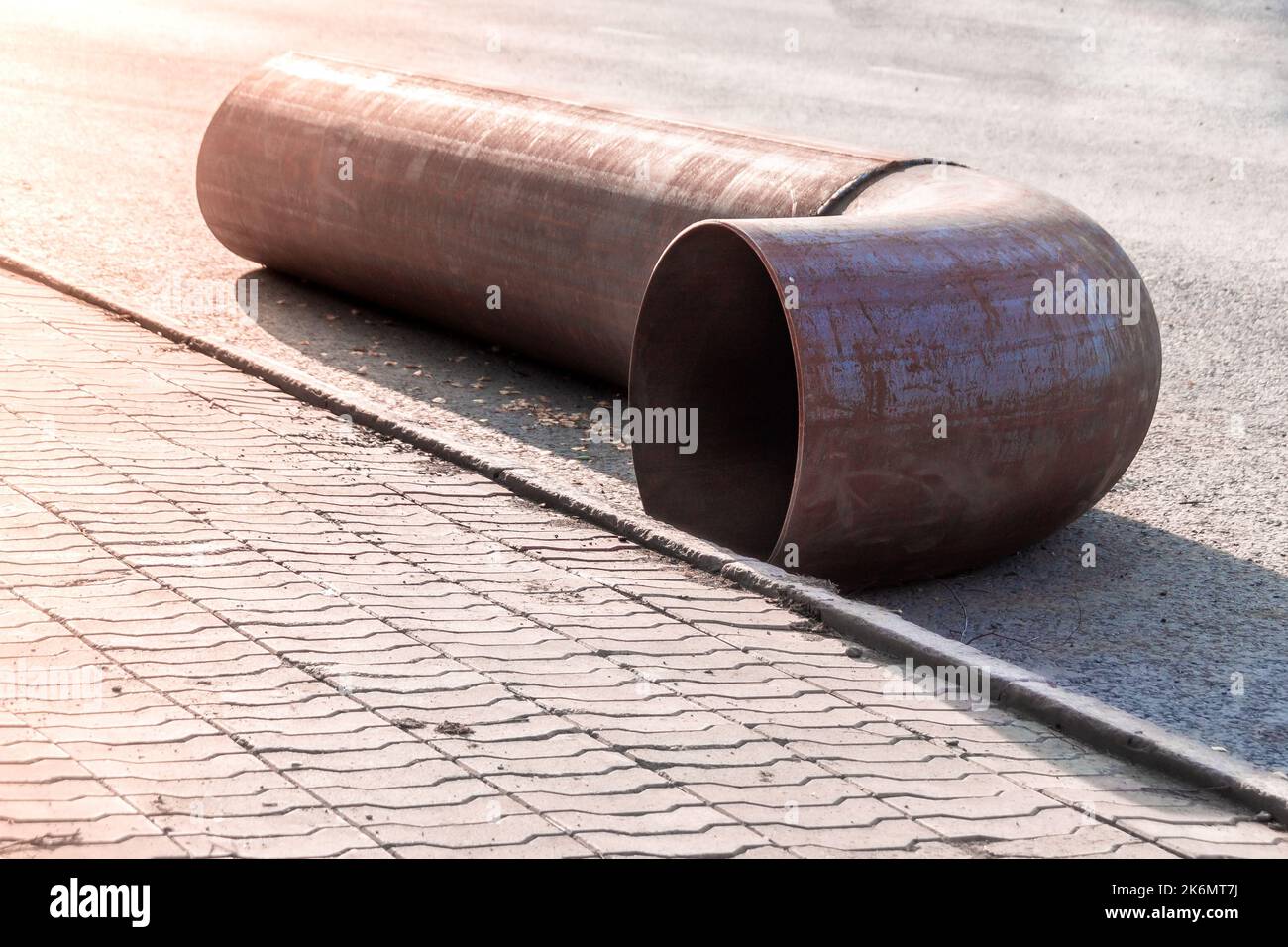 a new fitting pipe turn lies on the pavement waiting for the repair of the main pipe, selective focus Stock Photo