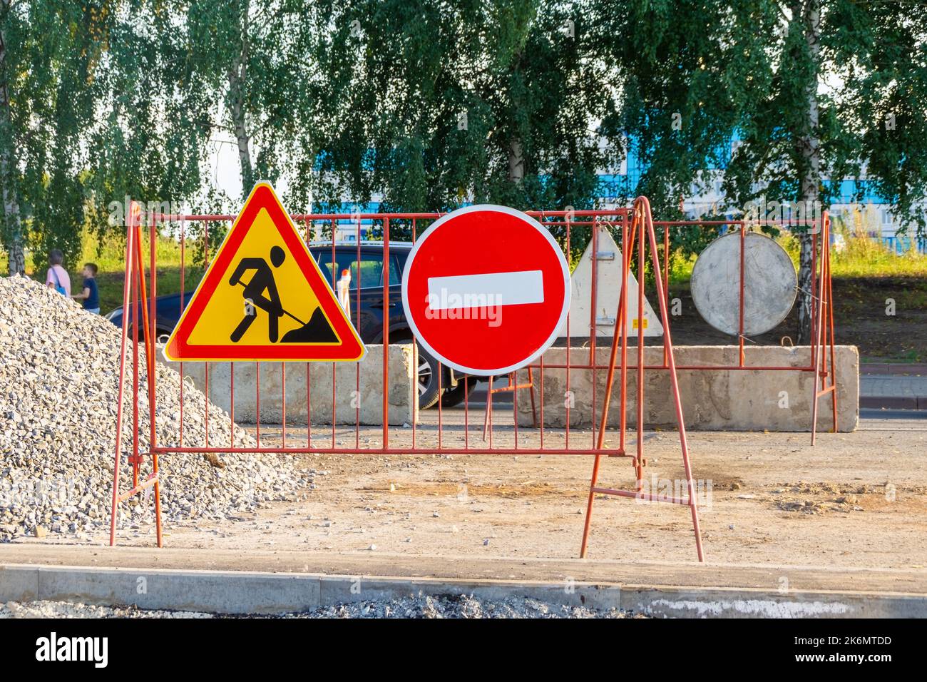 road works site protected by concrete blocks and fenced off with temporary warning signs and road signs, no entry signs and road works in progress beh Stock Photo