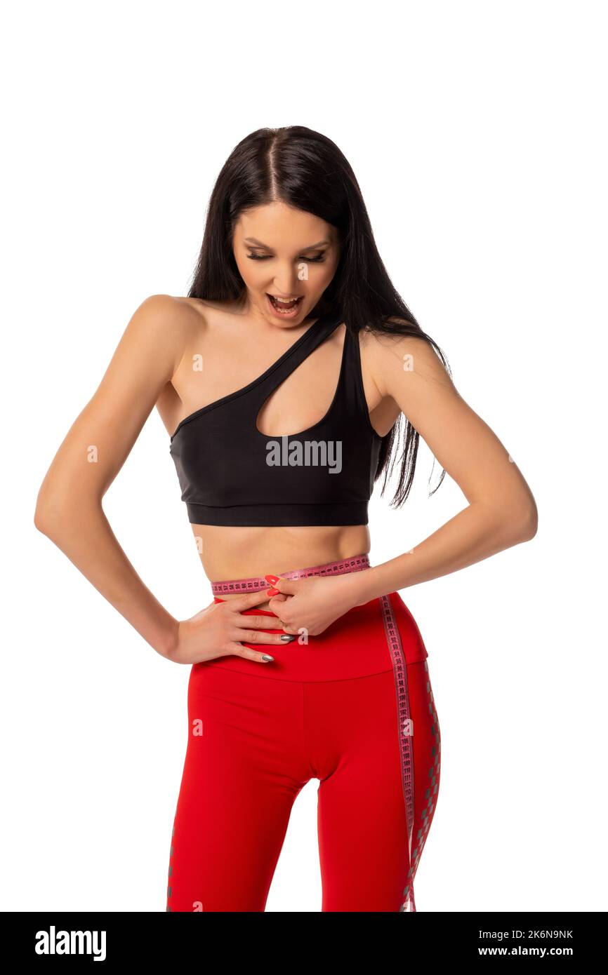 Slim sportswoman measuring waist with tape and in white studio Stock Photo