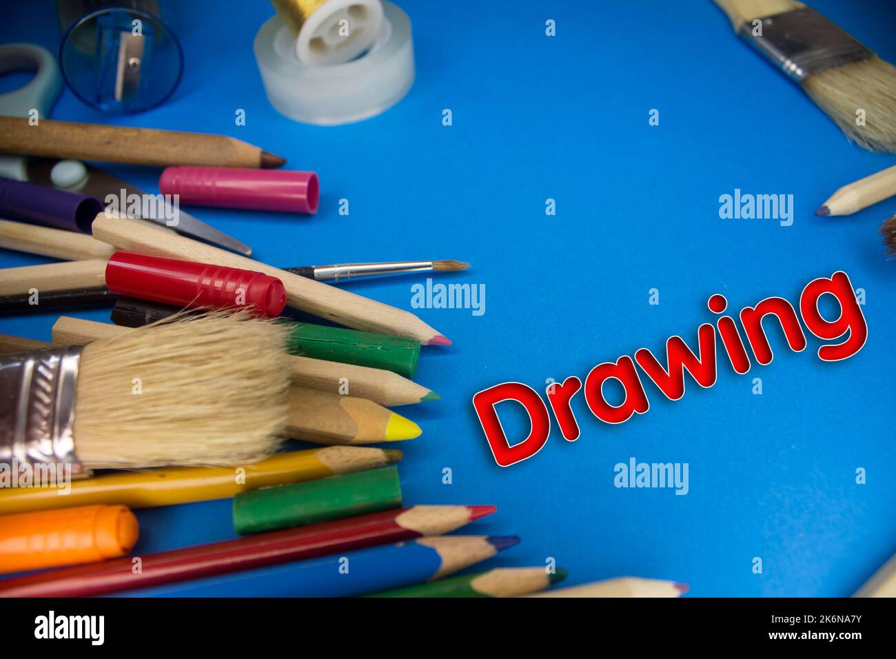 Overhead shot of school supplies with Drawing text. Brushes, pencils