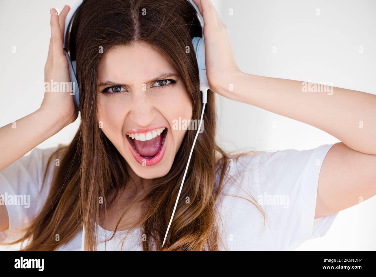 I cant hear you over the sound of this craziness. a young woman listening to music against a studio background. Stock Photo