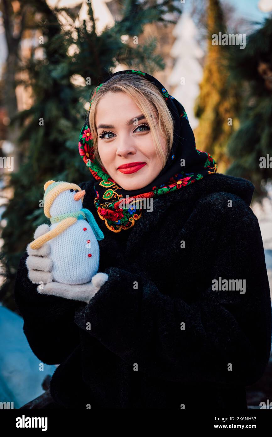 Beautiful young woman in a national Ukrainian headscarf holds a snowman  Stock Photo