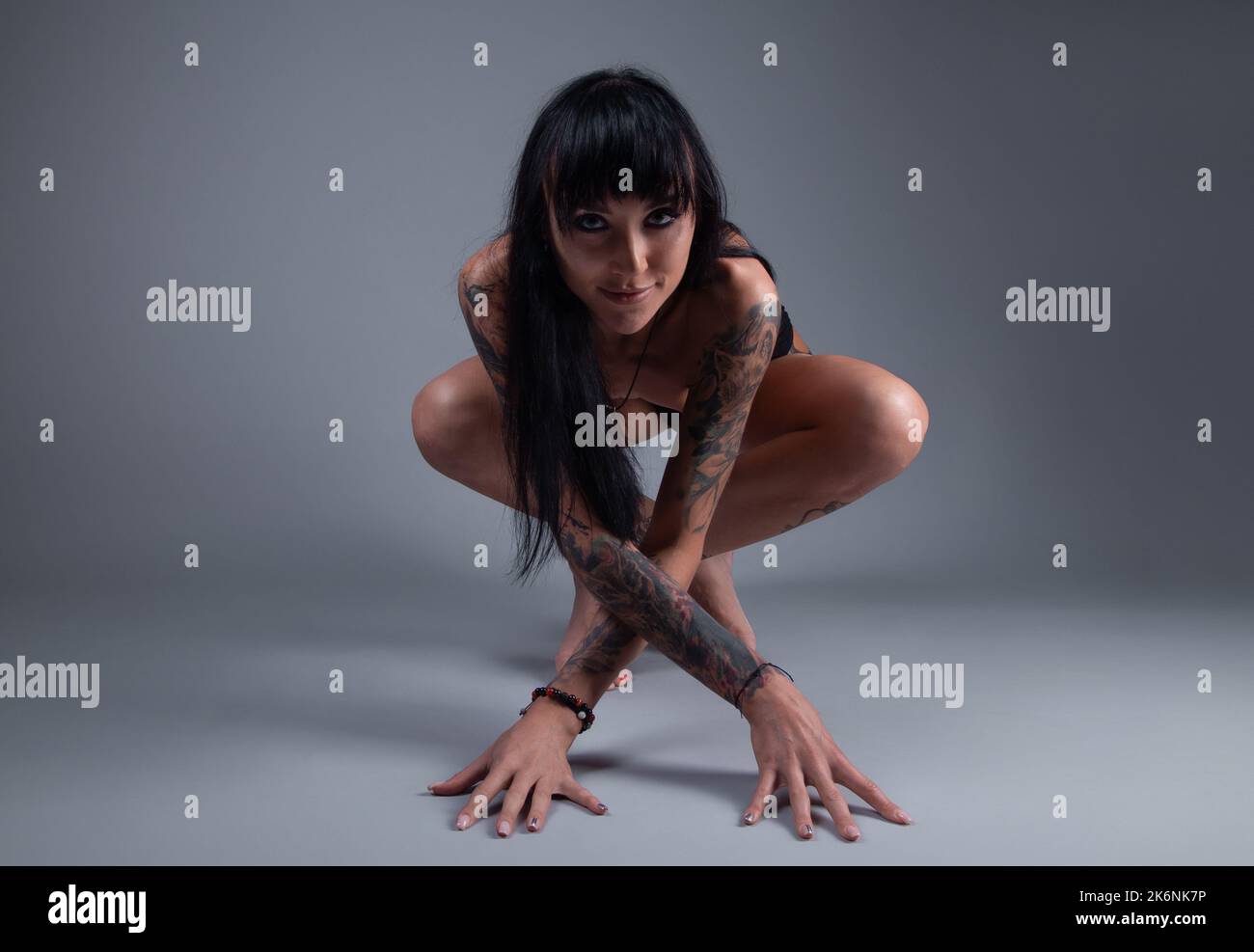 Photo of the nude brunette girl with tattoo sitting on the floor Stock Photo