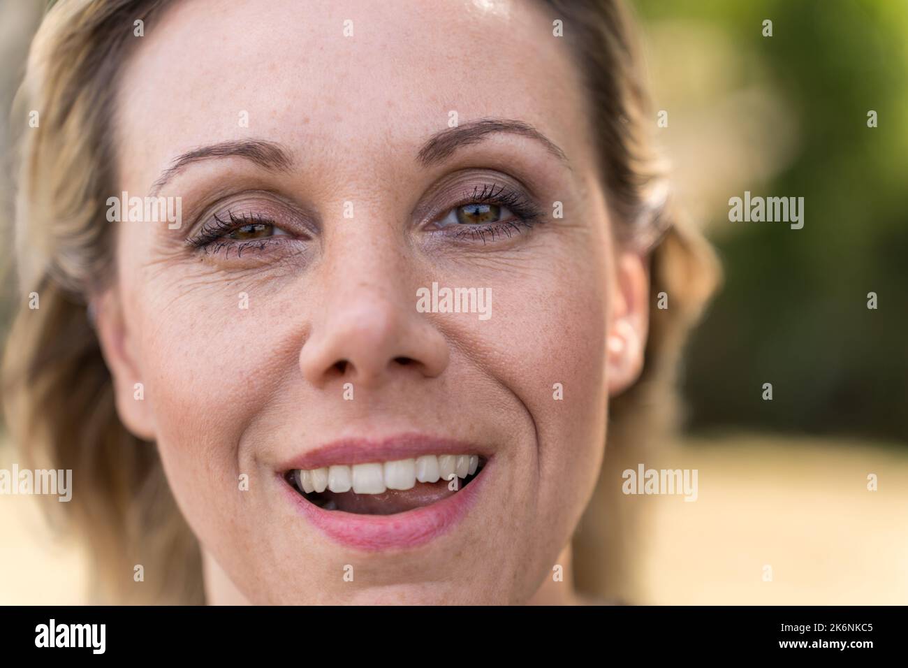 Close up of the face of an attractive blonde mature woman in her forties, with a mischievous smile and a winking eye Stock Photo