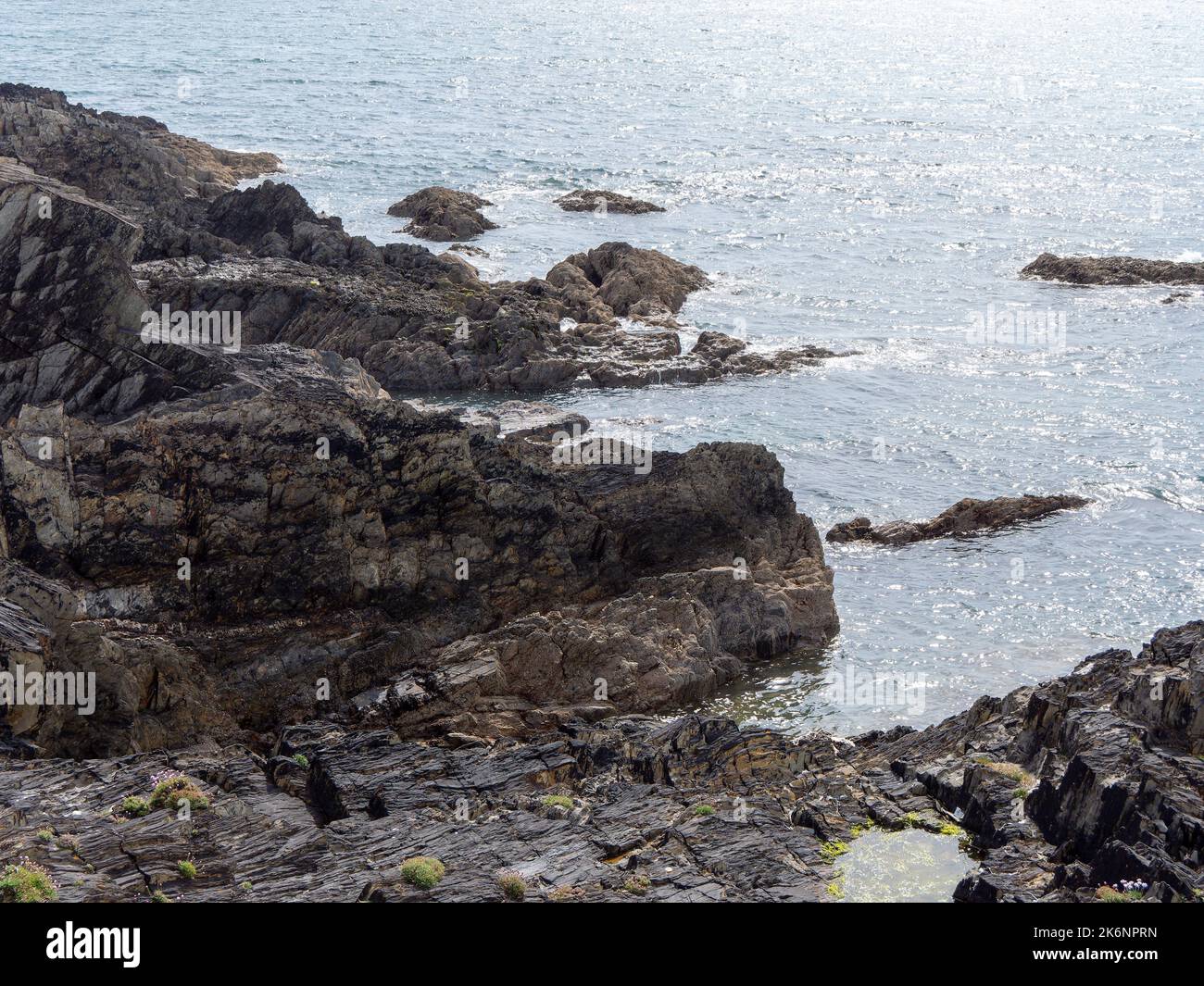 Exposed rocks on the shore. Seaside rocks in sunny weather, rock formation near body of water. Stock Photo