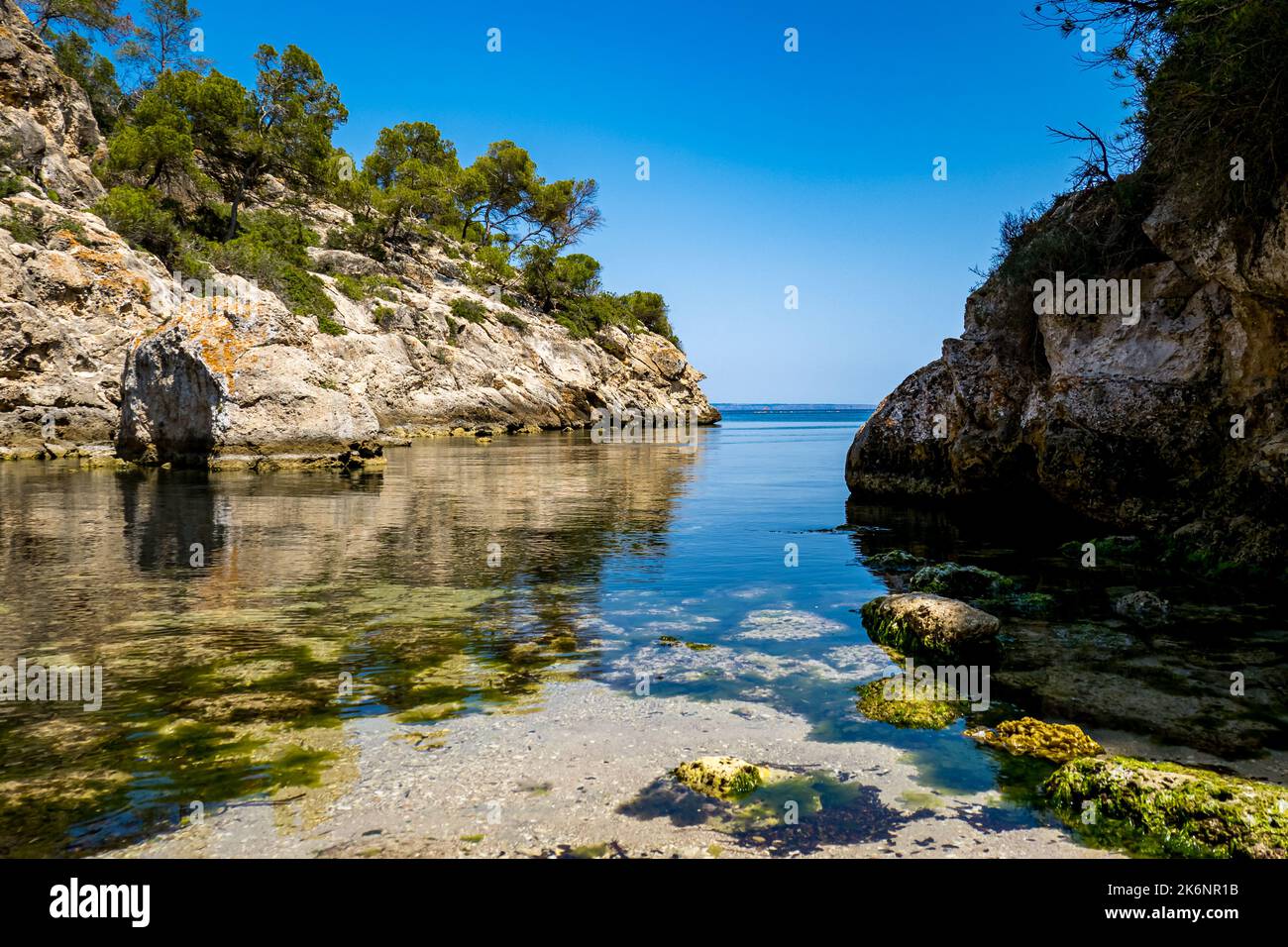View over calm water to the mediterranean sea from untapped natural cove Cala Figuera in the southwest of Mallorca in the Calviá area with seaweed. Stock Photo