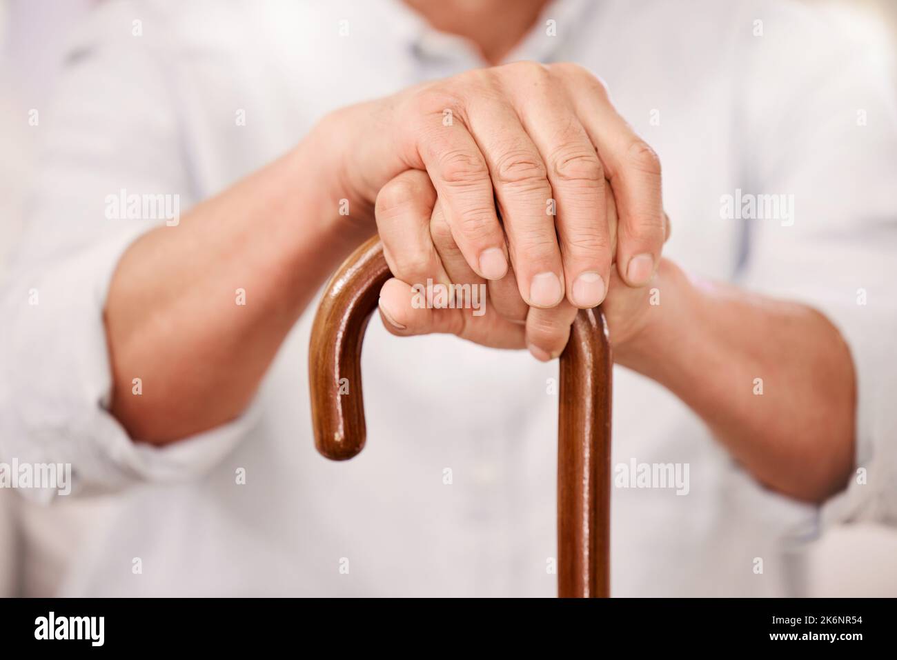 Its what keeps me moving. a senior man sitting at home with a wooden walking stick. Stock Photo