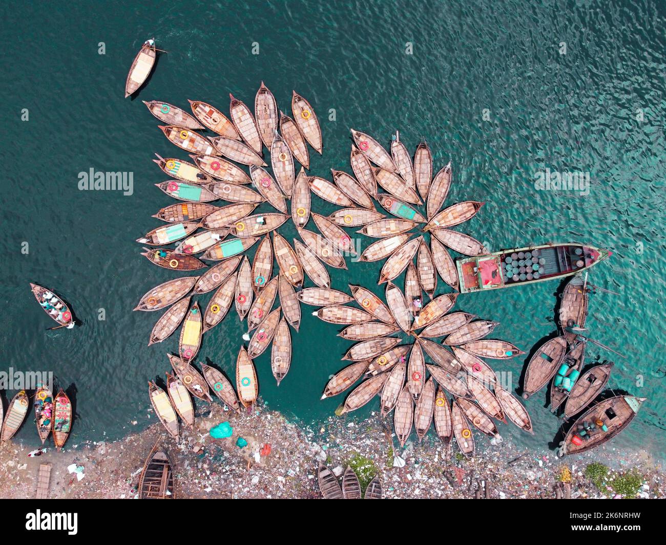 Hundreds of wooden boats fan out around their moorings in patterns which look like the petals of flower for a busy morning commute on Buriganga river. Stock Photo