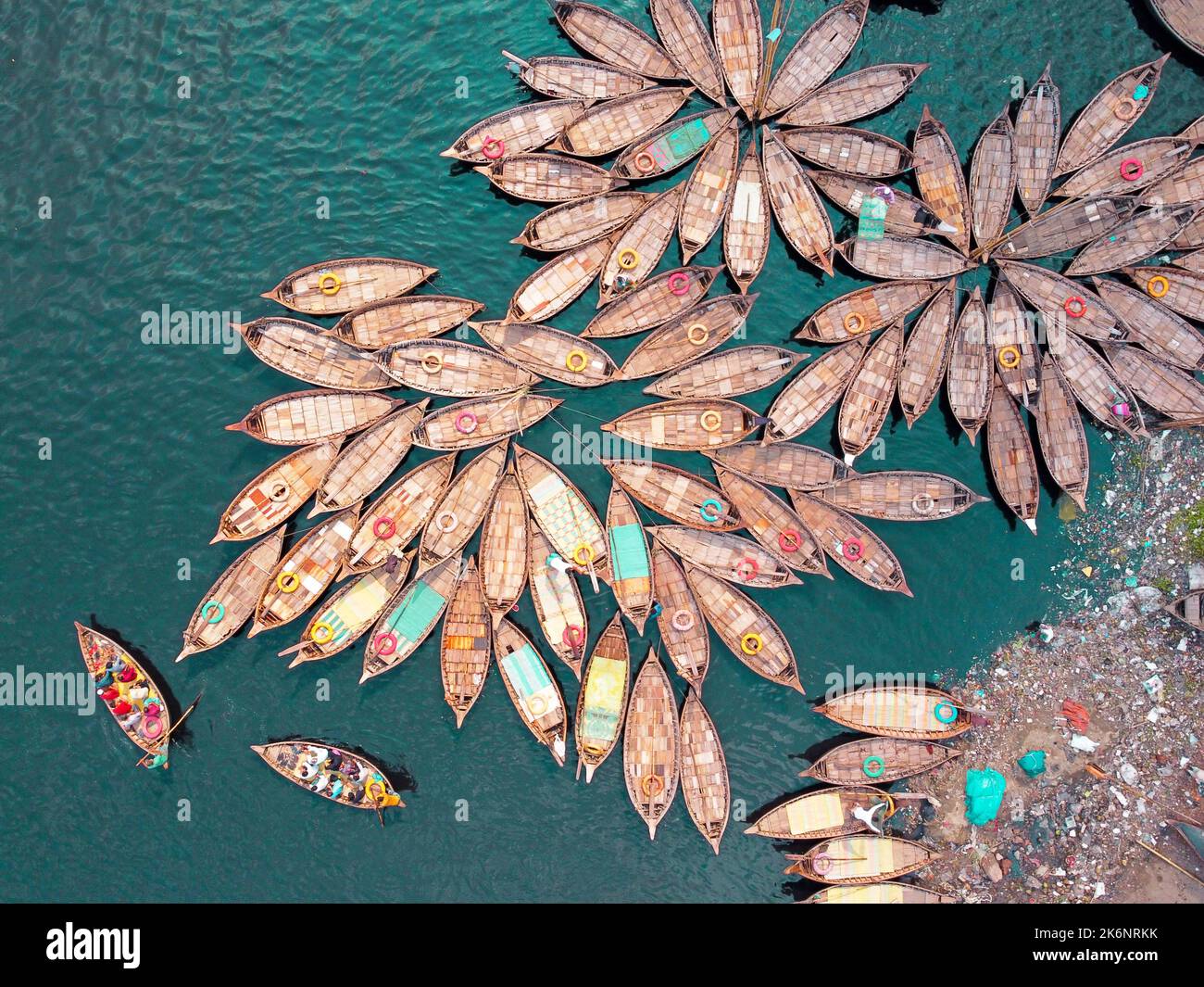 Hundreds of wooden boats fan out around their moorings in patterns which look like the petals of flower for a busy morning commute on Buriganga river. Stock Photo