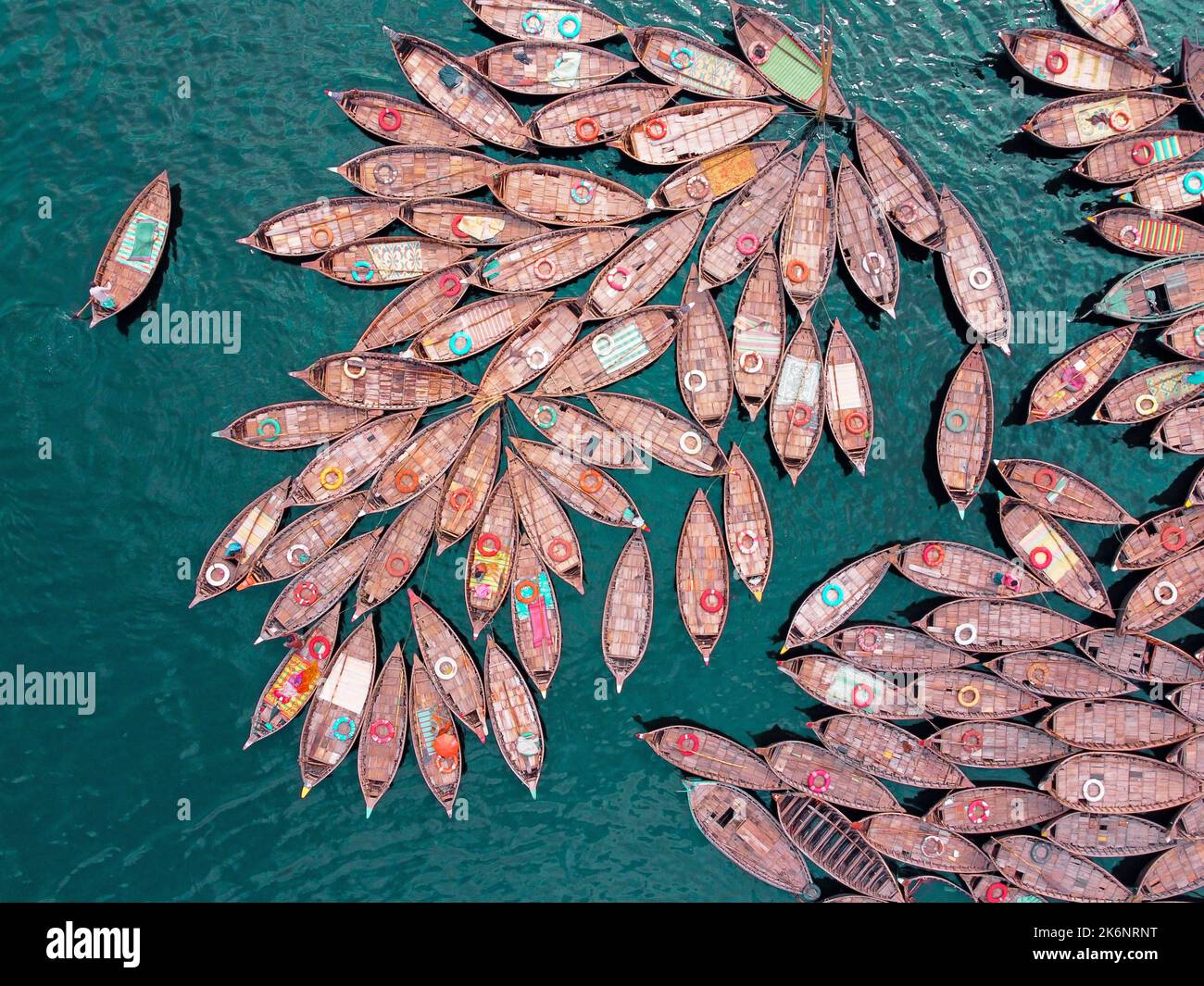 Hundreds of wooden boats fan out around their moorings in patterns which look like the petals of flower for a busy morning commute on Buriganga river. Stock Photo