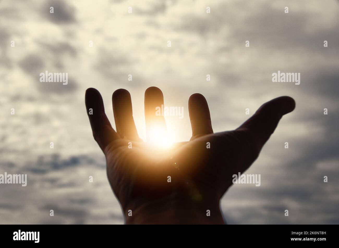 Light shining on hand with vintage sky color background. Stock Photo