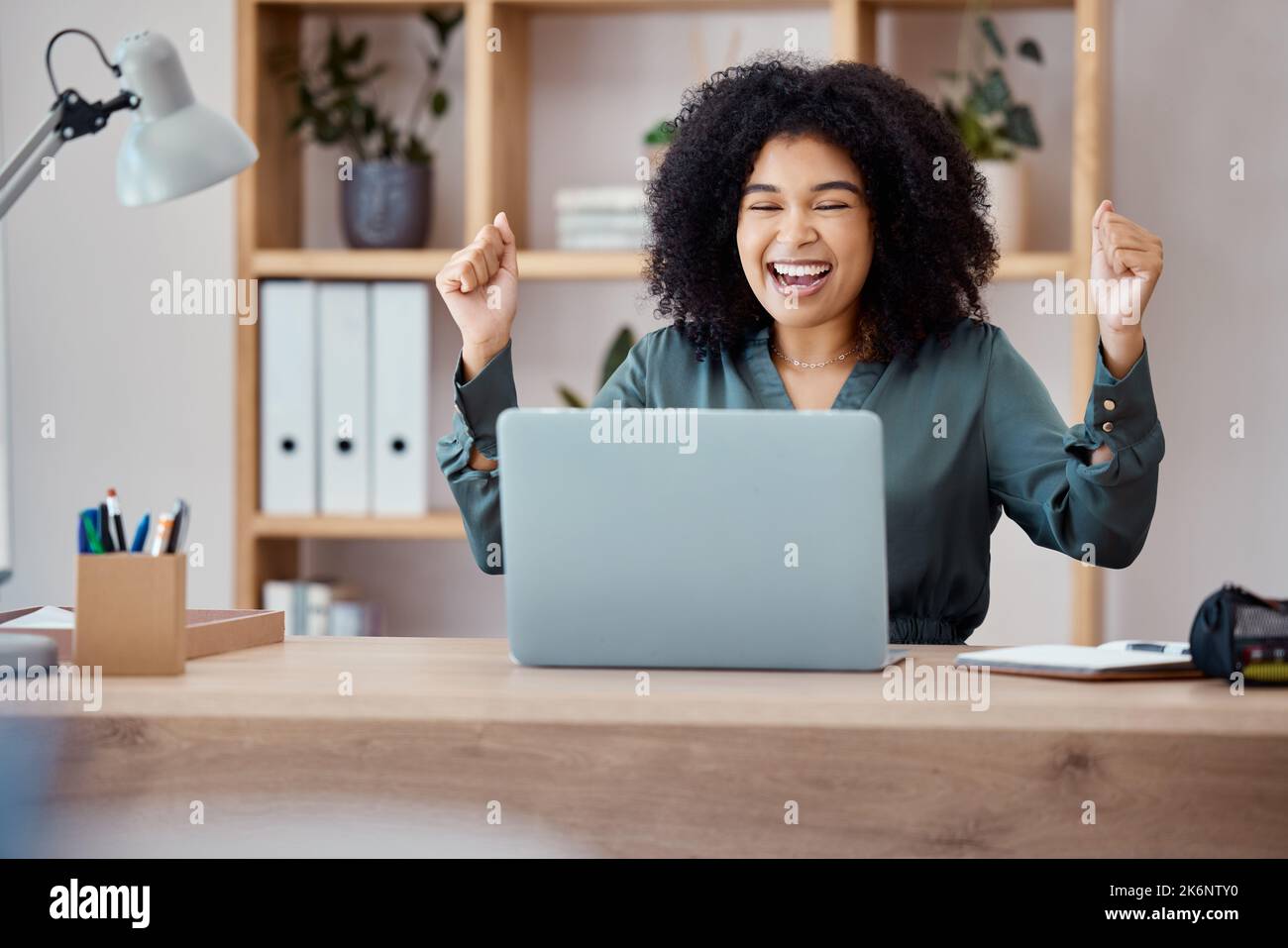 Laptop, success and business woman in celebration at her desk in modern corporate office. Happy, celebrate and professional employee from Mexico with Stock Photo