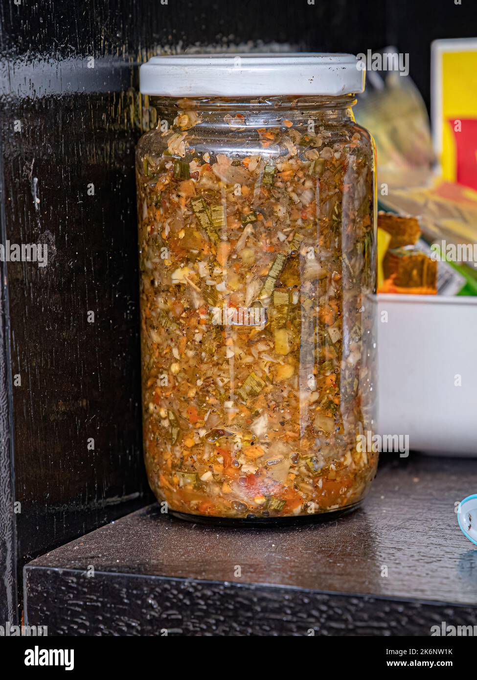 Seasoning jar made with yellow peppers, green peppers, red peppers, garlic, onions, chives, green onions, parsley, salt, olive oil, oregano and dried Stock Photo