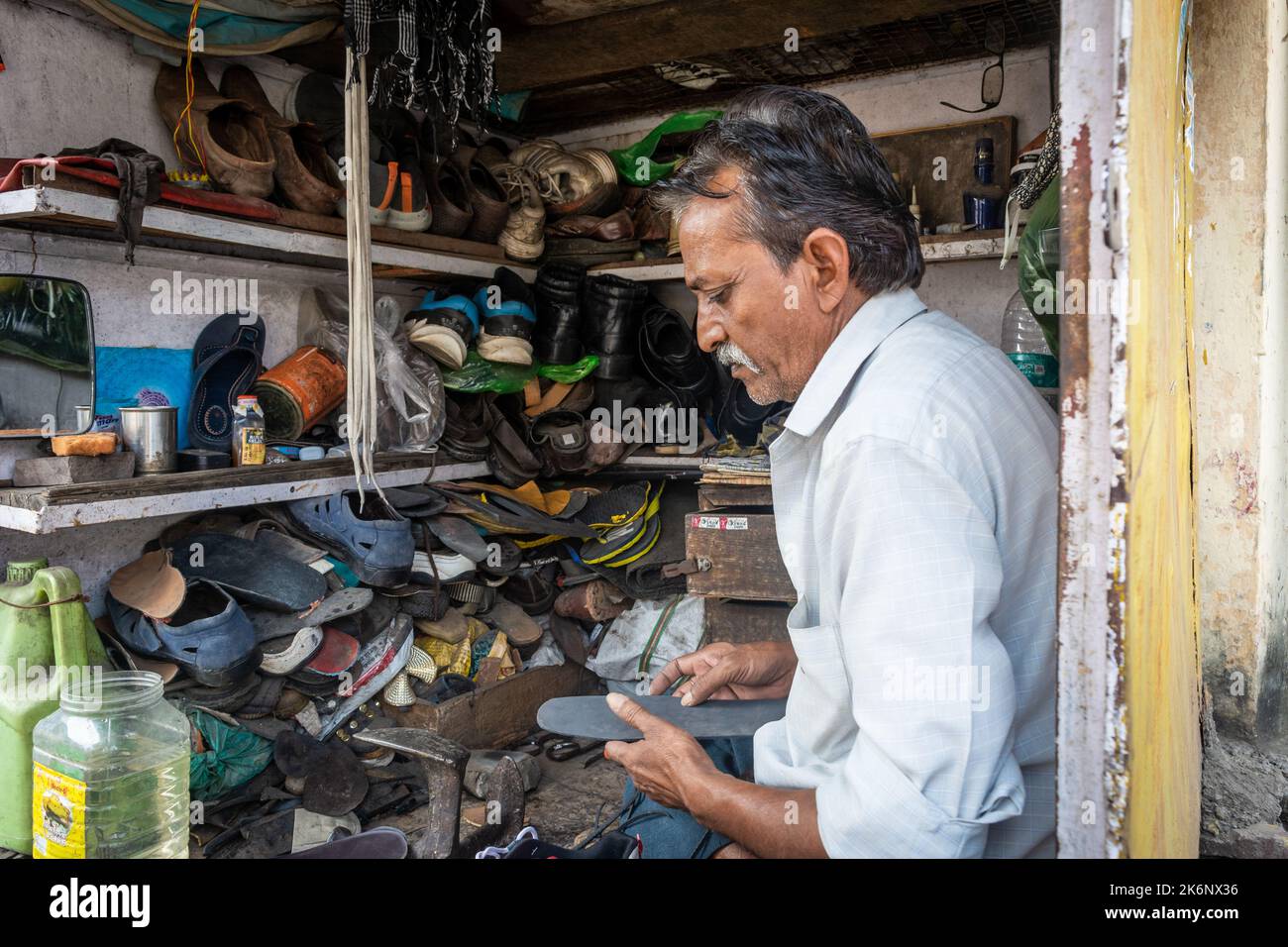 TIKAMGARH, MADHYA PRADESH, INDIA - MAY 14, 2022: An Indian cobbler working on shoe repair in his shop. Stock Photo