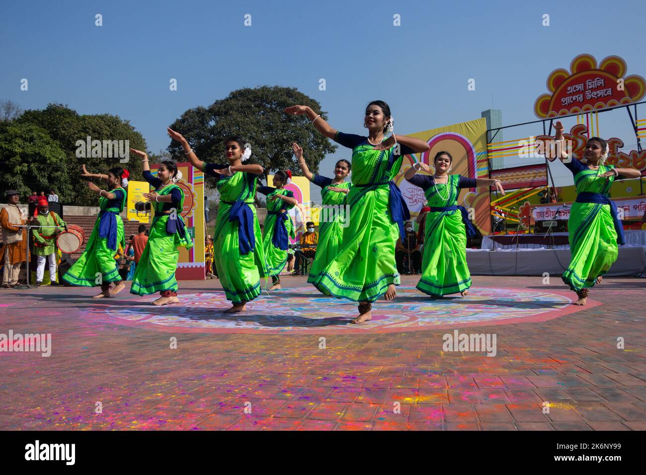 Women wear traditional dresses with floral ornaments and perform during