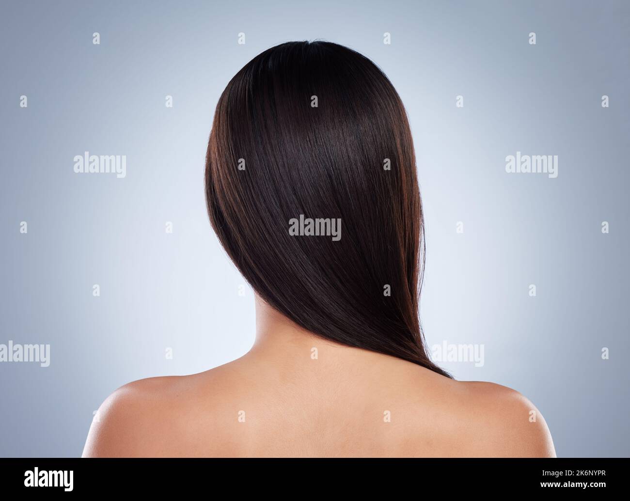 Rear view of brunette woman posing with her hair over her shoulder. Young mixed race woman with healthy smooth straight hair Stock Photo
