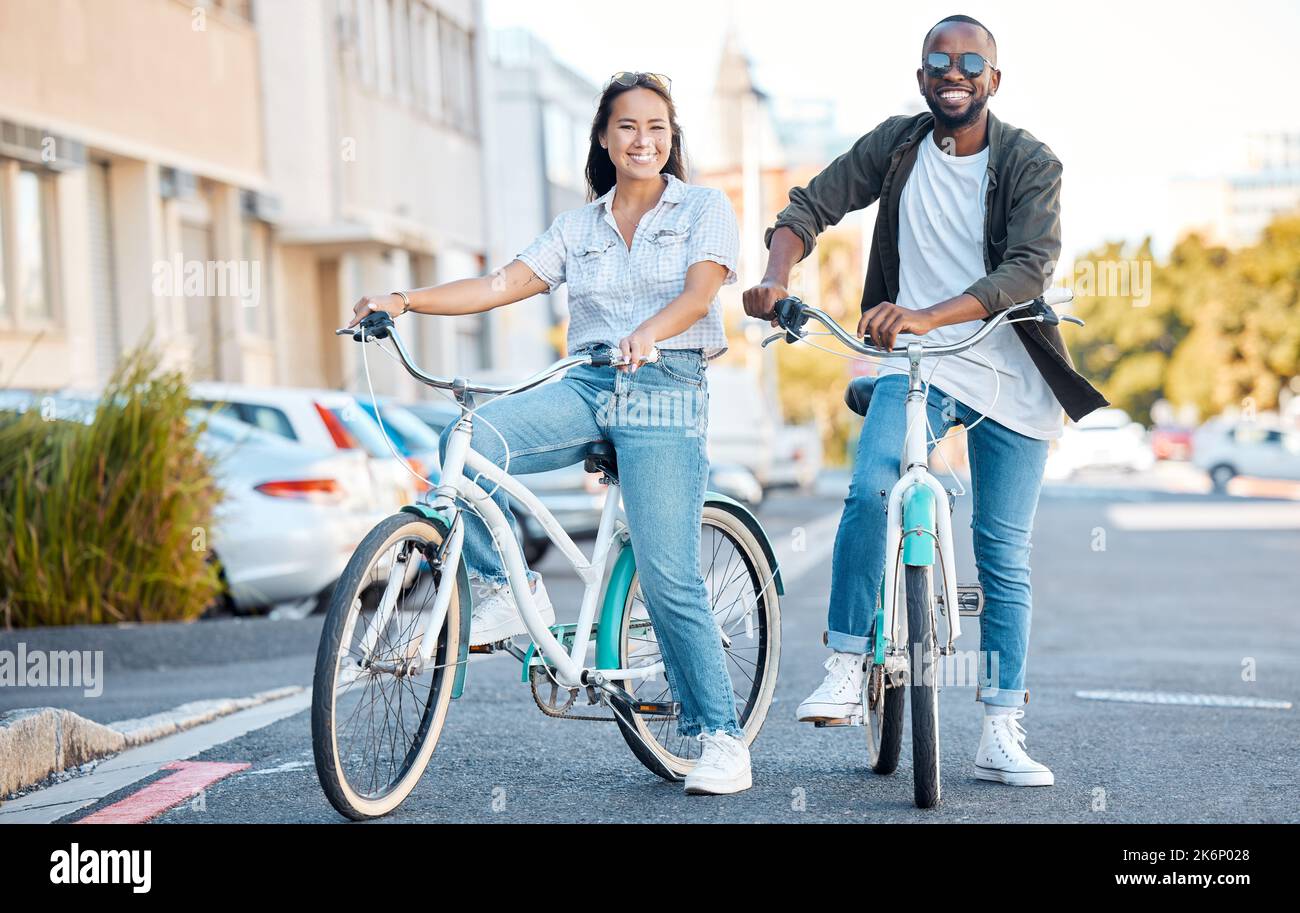 Bike, couple and travel with a black man and asian woman cycling in the city for sightseeing or adventure. Bicycle, carbon footprint and love with a Stock Photo