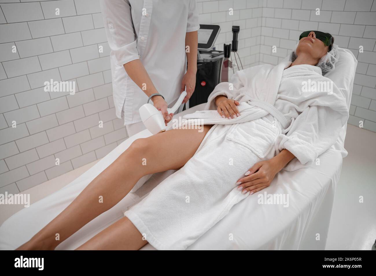 Woman getting hair removing procedure on legs. Laser epilation and cosmetology in beauty salon Stock Photo