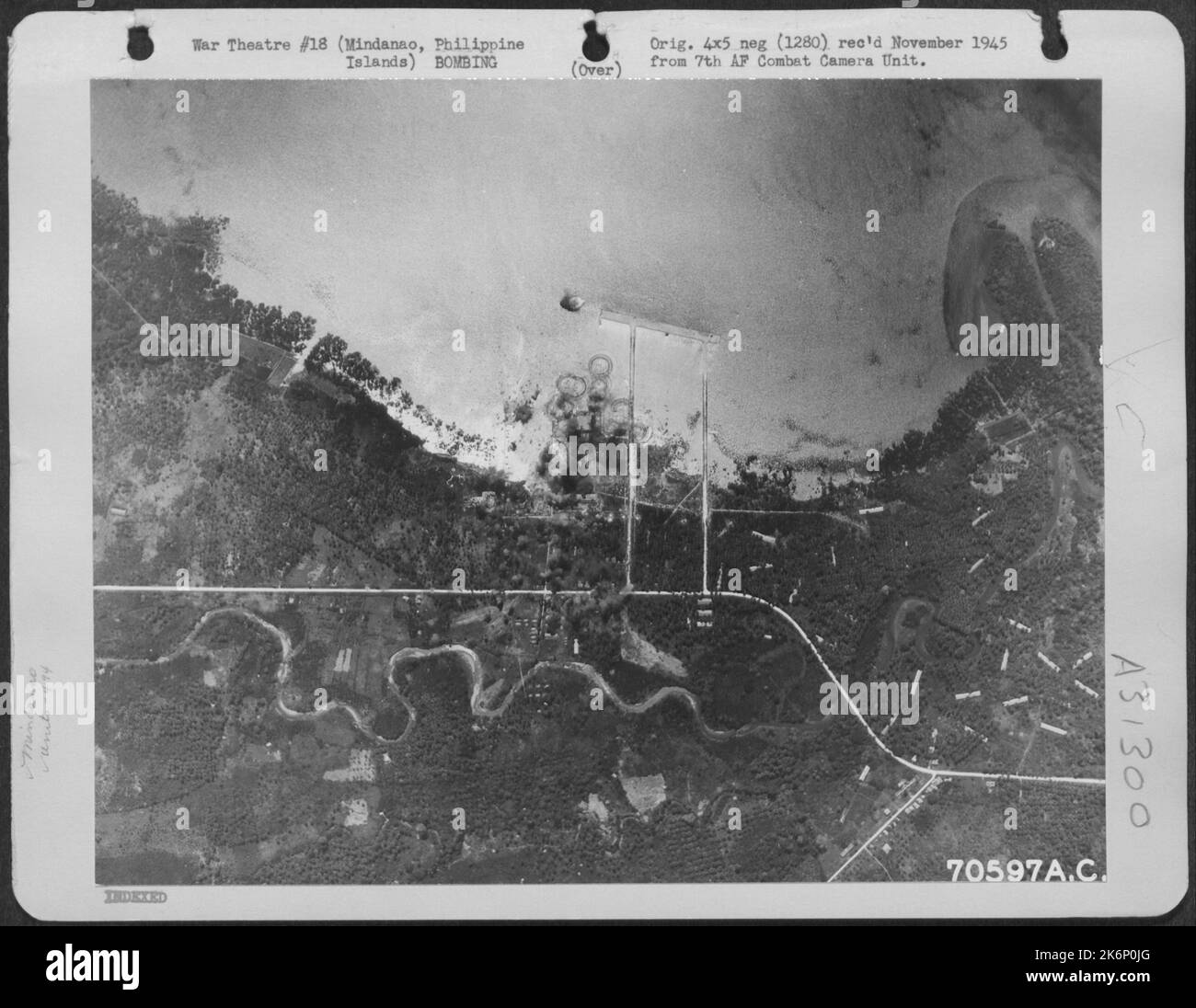 Bombs, dropped from 494th Bomb Group Consolidated B-24 'Liberators,' burst on the target; a Japanese installation south-east of the village of Bunawan on the island of Mindanao in the Philippines. 4 April 1945. Stock Photo