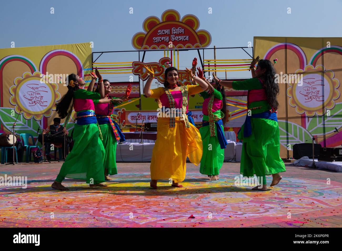 Women wear traditional dresses with floral ornaments and perform during