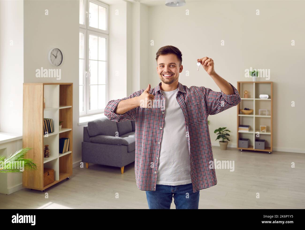 Happy young man holding keys to his new house or apartment and showing ...