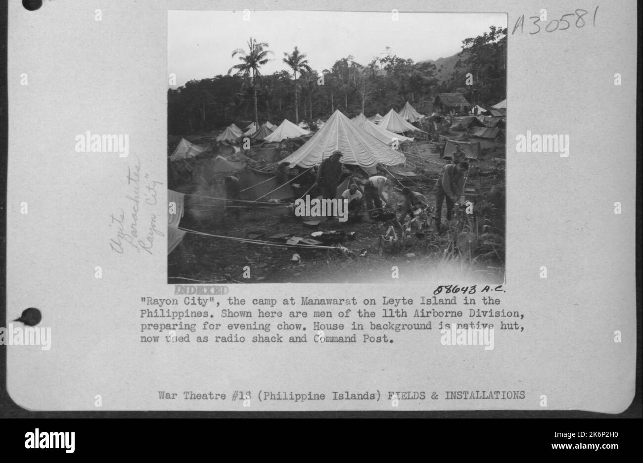 'Rayon City,' the camp at Manawarat on Leyte Island in the Philippines. Shown here are men of the 11th Airborne Division, preparing for evening chow. House in background is native hut, now used as radio shack and Command Post. Stock Photo