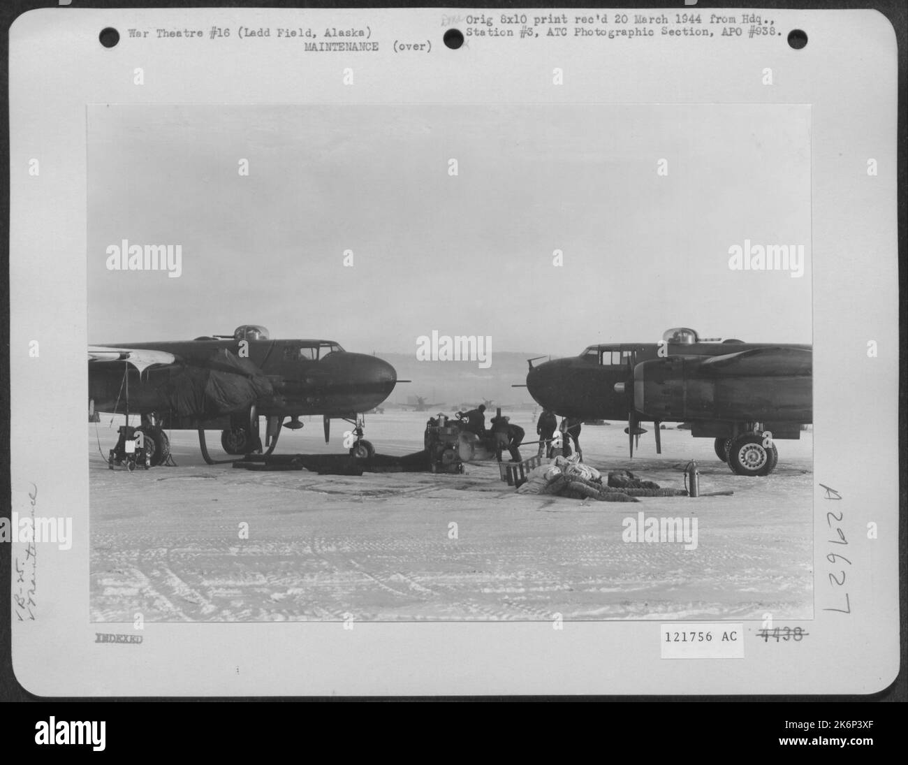 Because Of The Extremely Low Temperature, An Engine Heater Is Used On A North American B-25. At Right A Tractor Is Hooked To Another B-25; Note The Heating Equipment Lying On The Ground Beside The Plane. Ladd Field, Alaska, 9 February 1944. Stock Photo