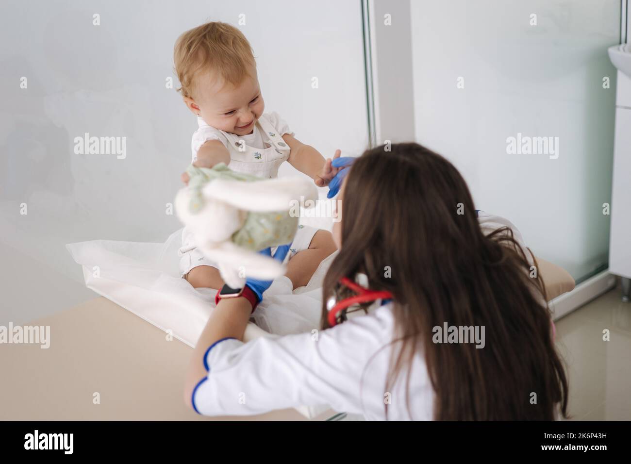 Little patient with soft toy rabbit. Young friendly smiling female ...