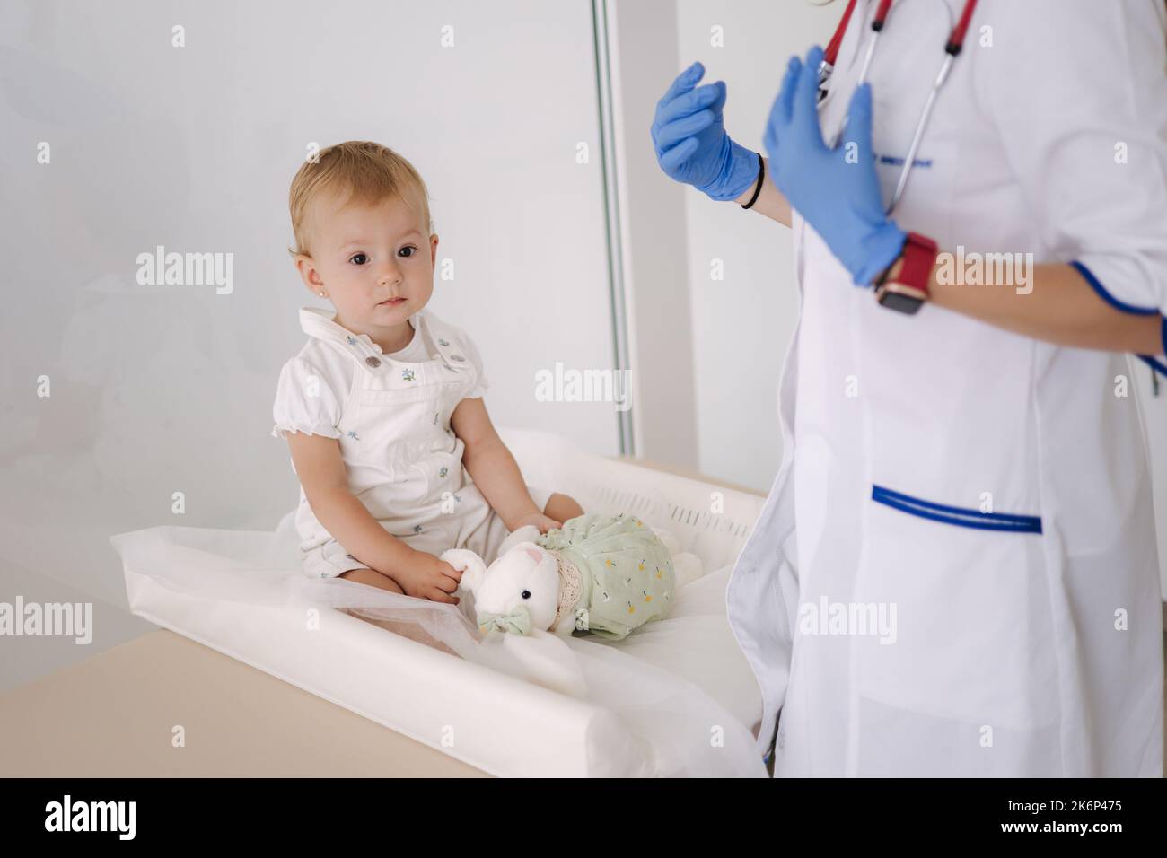 Little patient with soft toy rabbit. Young friendly smiling female ...