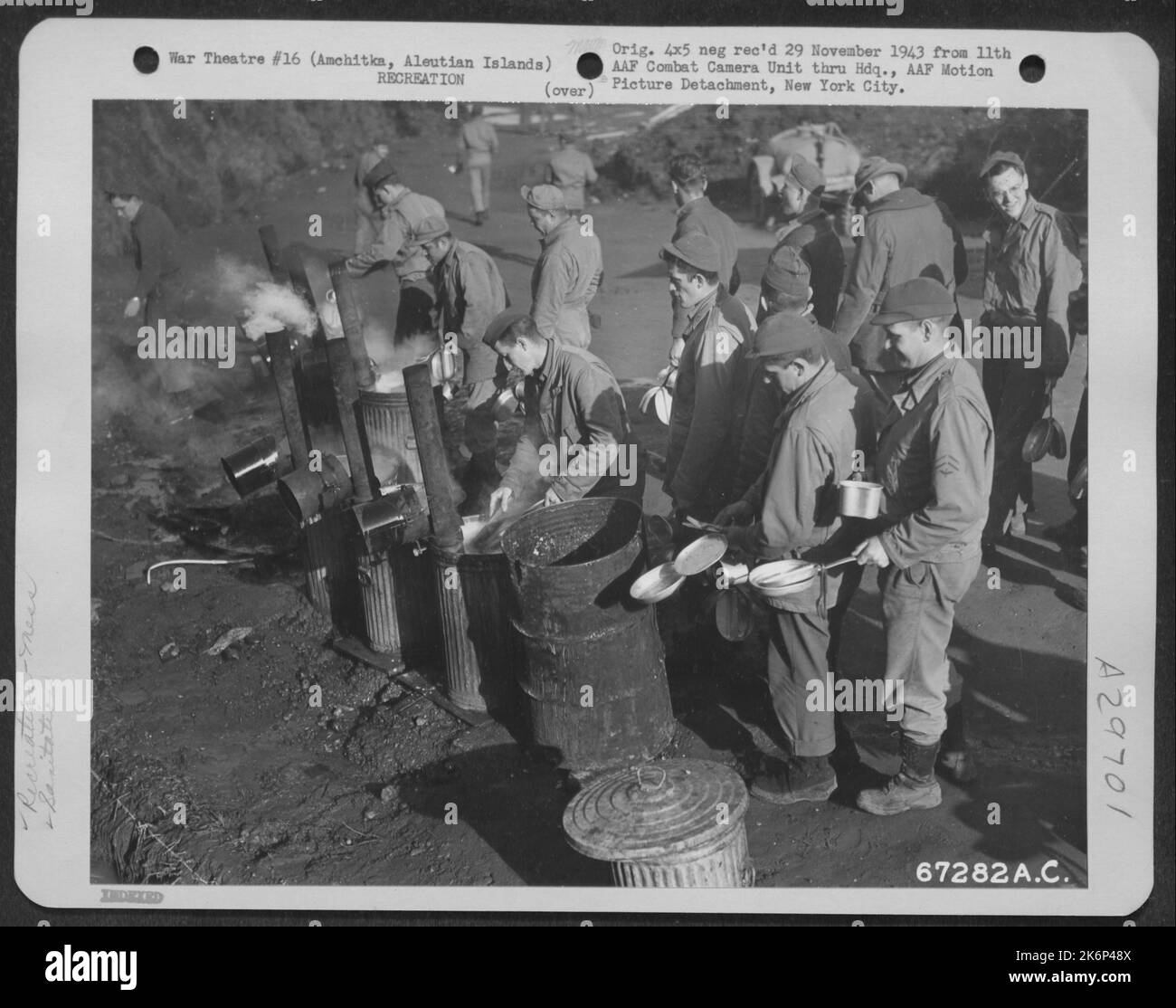 Troops, stationed at Amchitka, Aleutian Islands, wash their mess kits in cans of scalding water. The men in the background are lined up for chow. 10 October 1943. Stock Photo