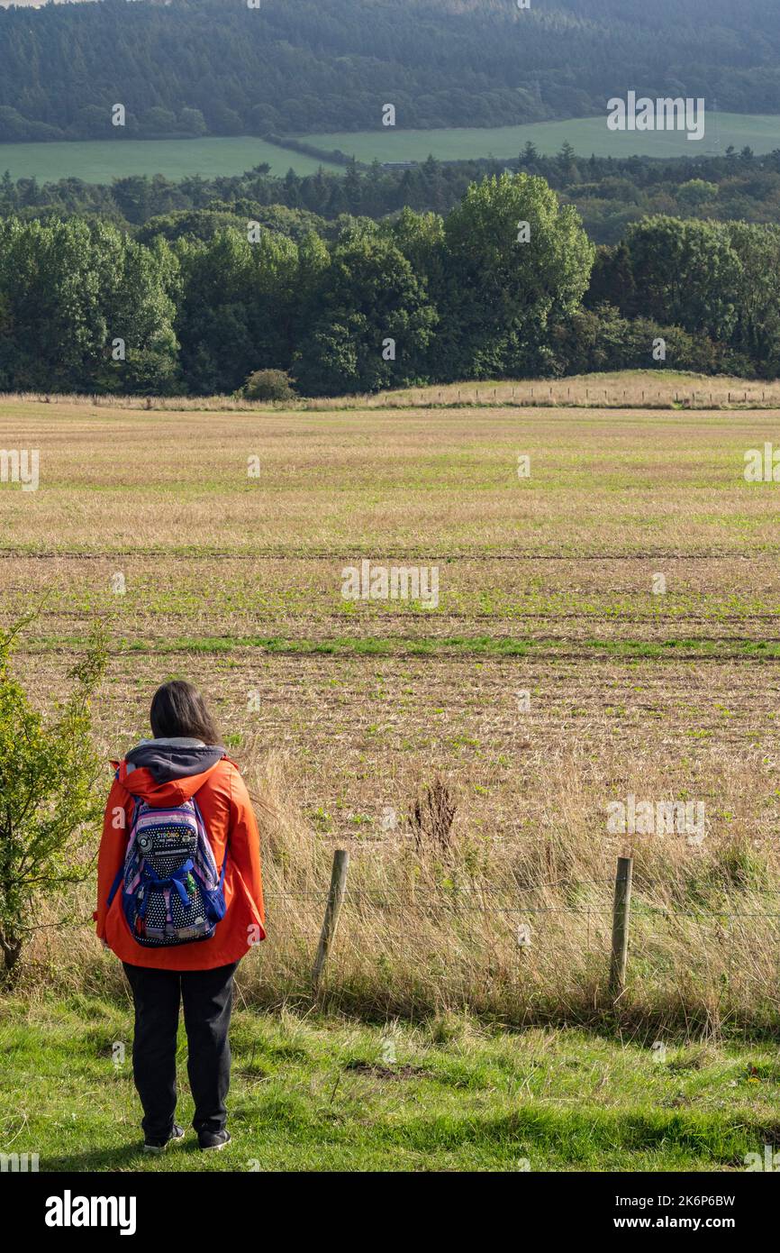girl in orange coat with back pack enjoying the view in north yorkshire, UK Stock Photo