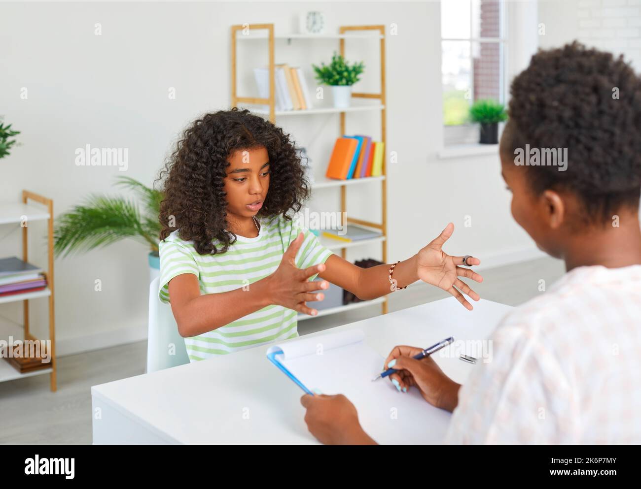 Girl is taking exam to teacher in humanities subject, actively gesticulating. Story, presentation, composition, literature. Stock Photo