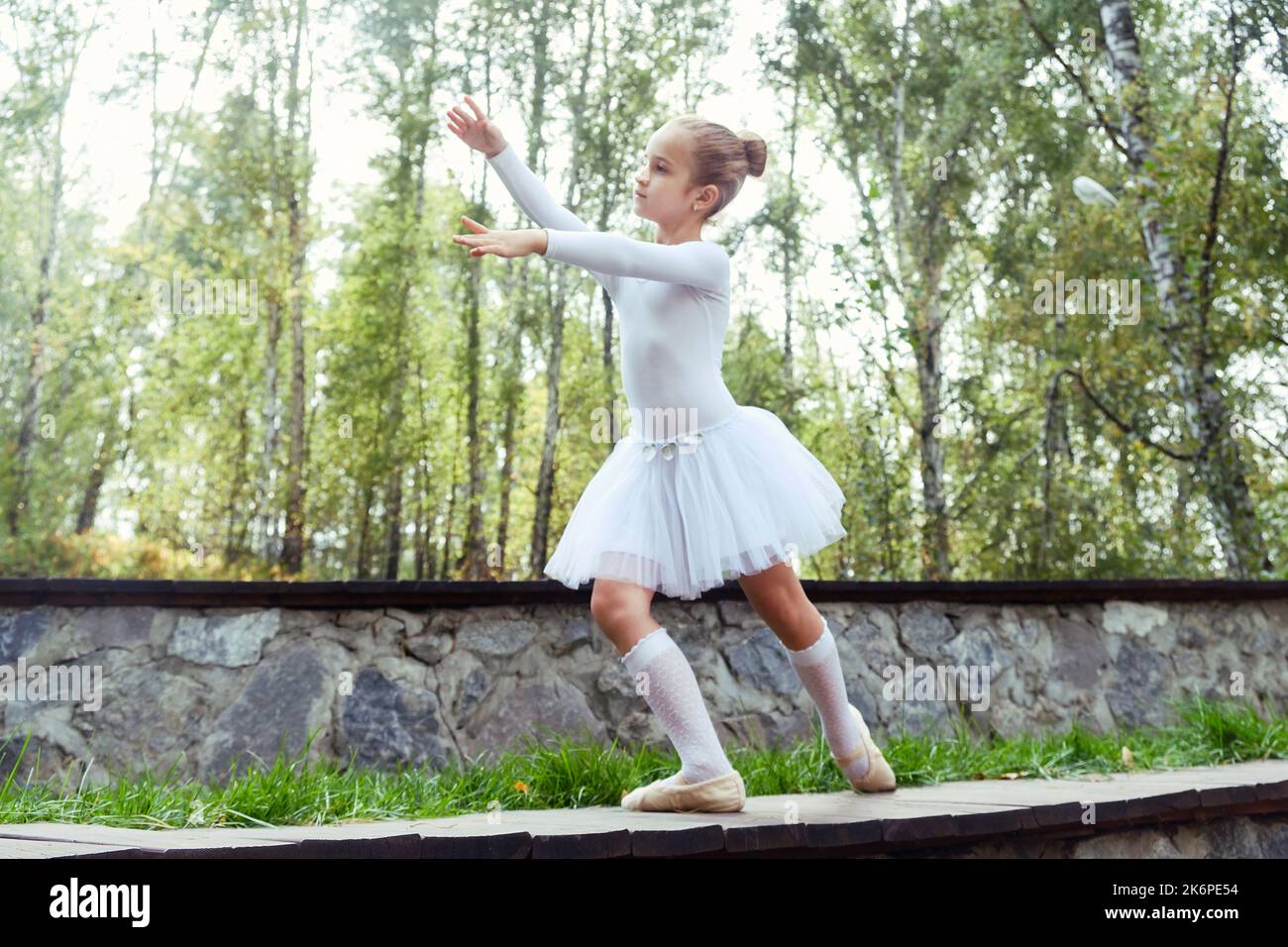 a little ballerina girl shows elements of choreography on a summer day