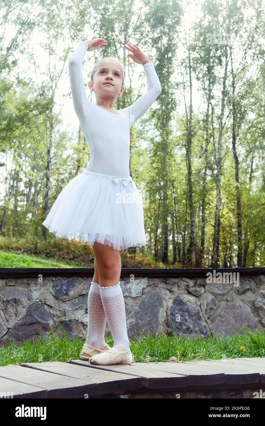 a little ballerina girl shows elements of choreography on a summer day