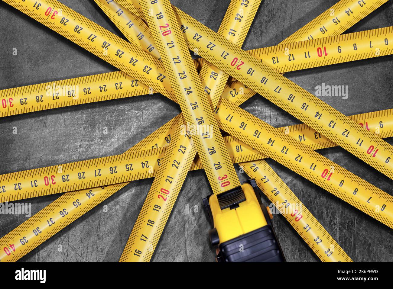 Large group of yellow and orange tape measures on a silver metal