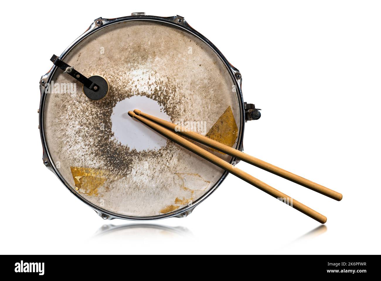Closeup of two wooden drumsticks and an old metallic snare drum