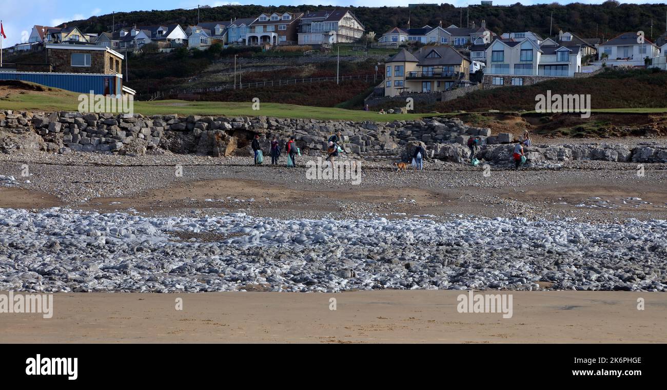 A group of fine people collecting all the litter on the beach after the tide has brought in more rubbish to add to what was left on the beach. Stock Photo