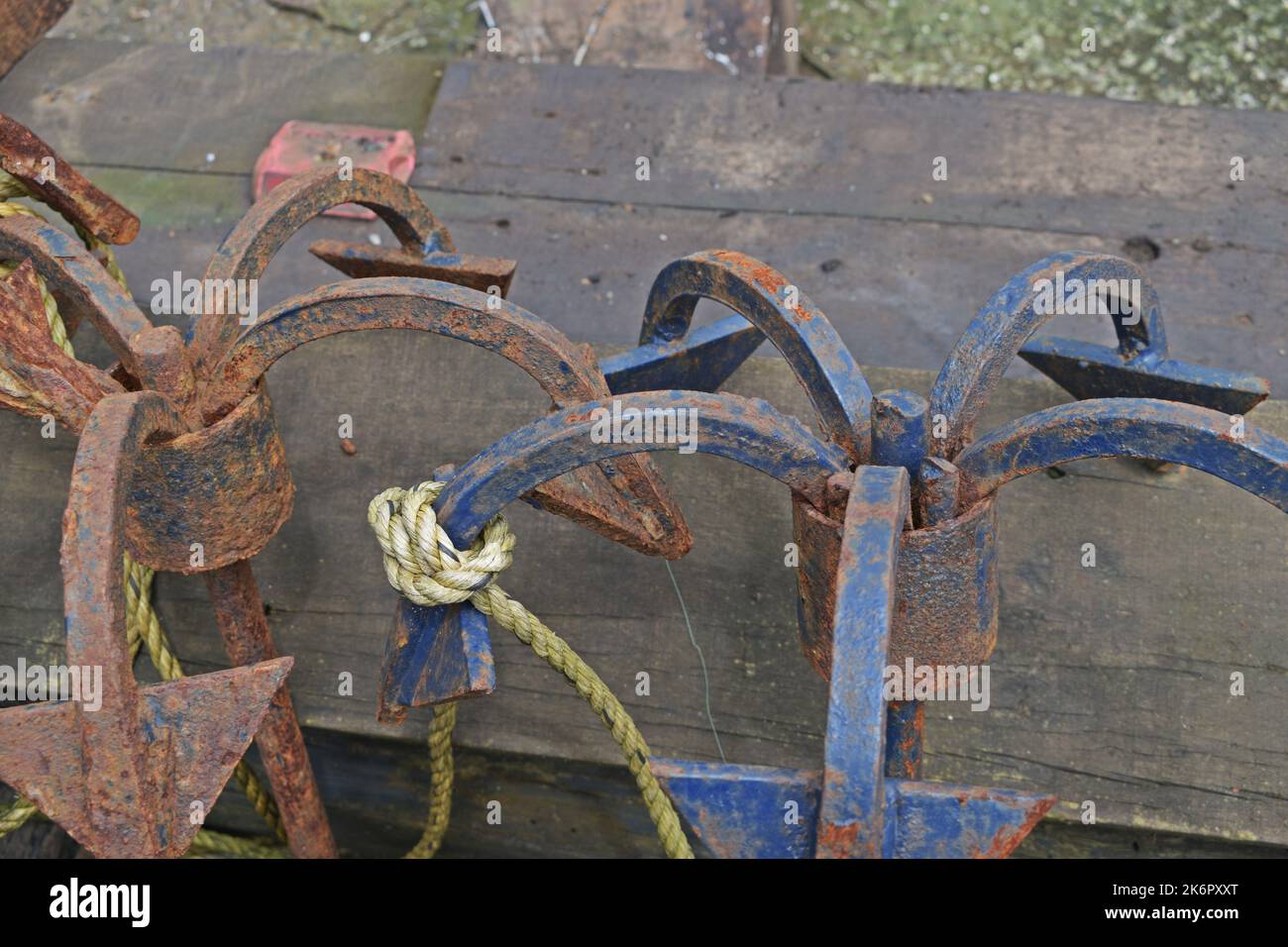 Rusty Anchors and Maritime Equipment on a Wooden Dock at Daytime Stock Photo