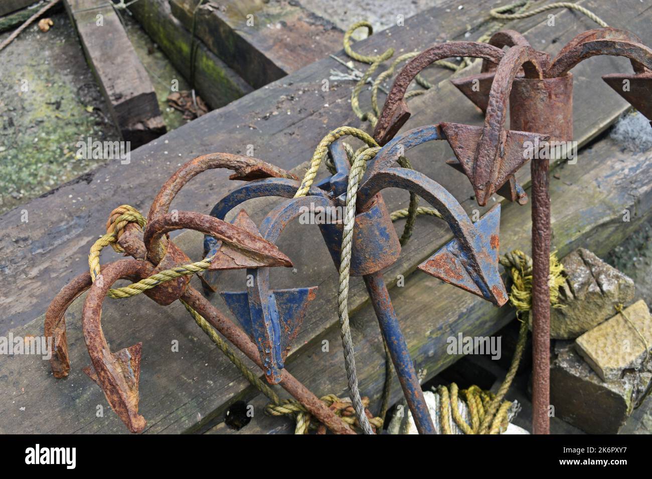 Rusty Anchors and Maritime Equipment on a Wooden Dock at Daytime Stock Photo