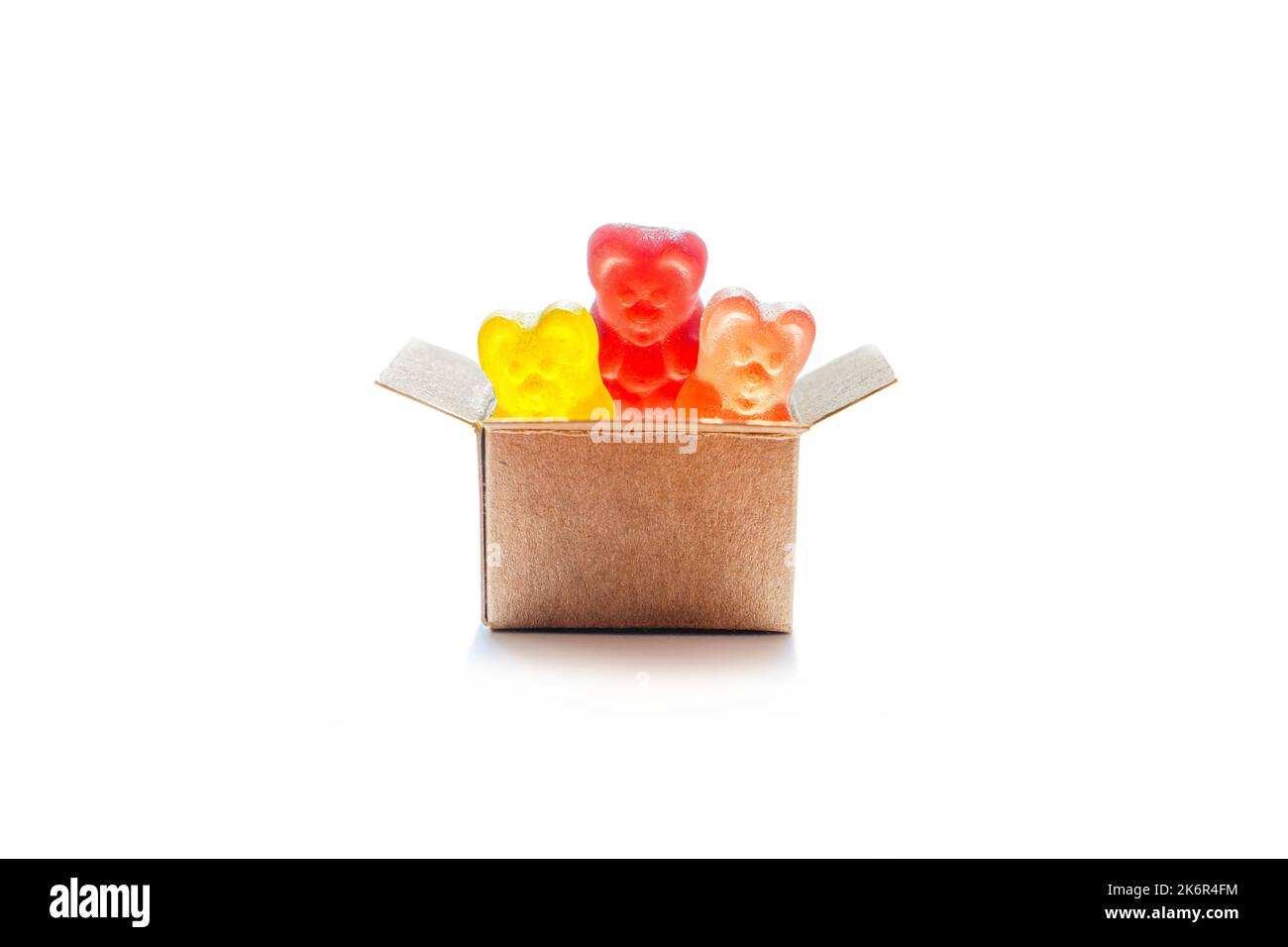 Miniature shipping box full of colorful gummy bears candies isolated on white background. Buying sweeties online. Stock Photo