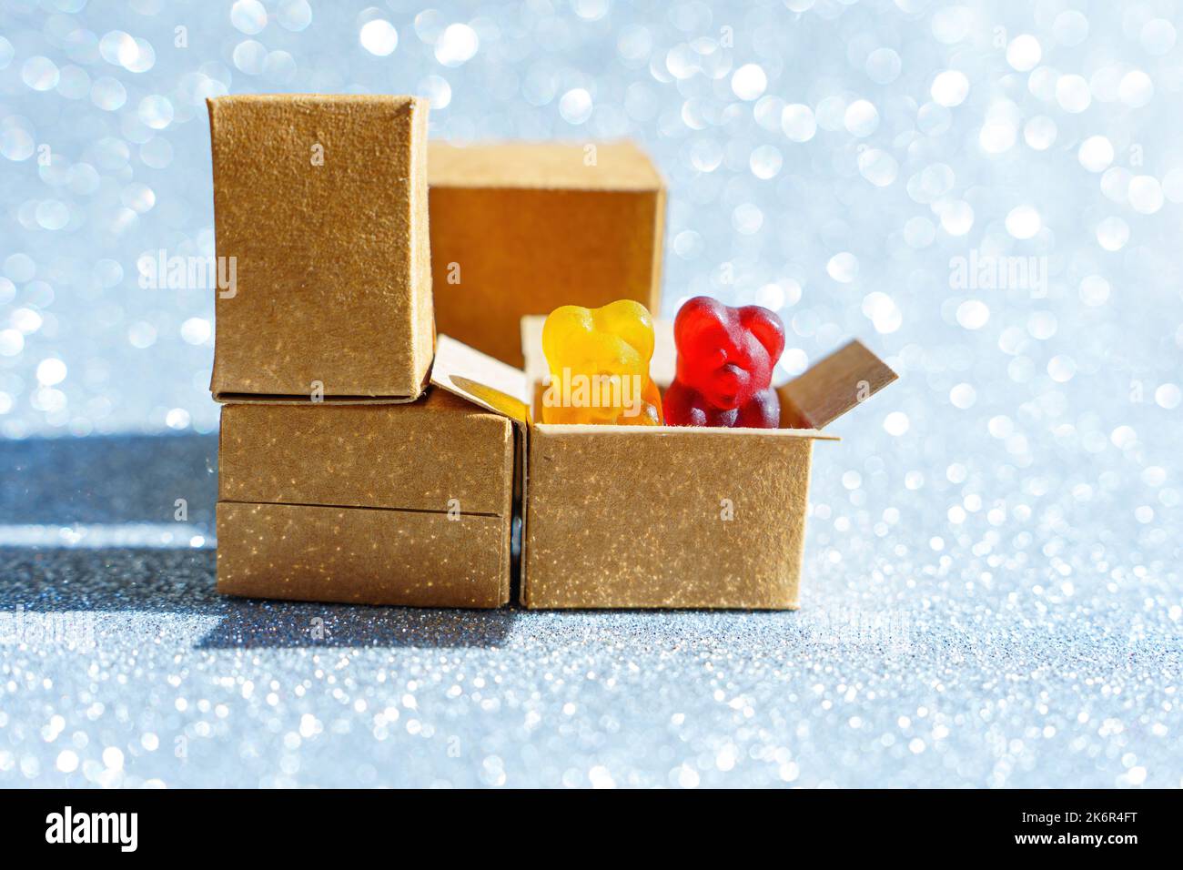 Two gummy bear candies peeping out of a shipping box isolated on a