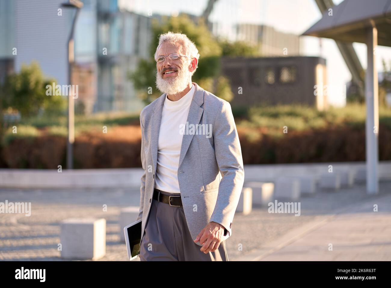 Happy stylish old professional business man walking outdoors in big city. Stock Photo