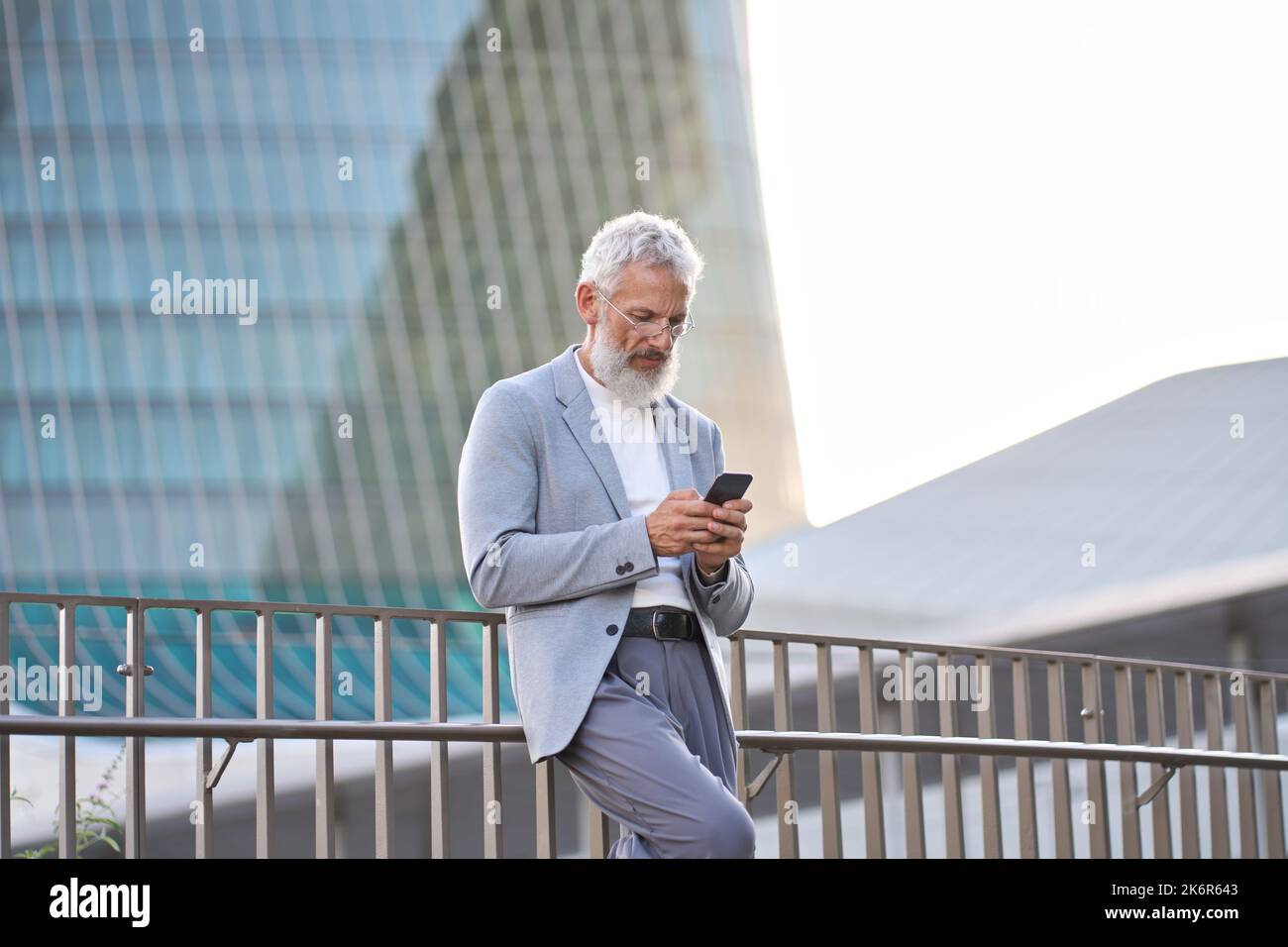 Stylish old professional business man using mobile tech on cell phone outside. Stock Photo