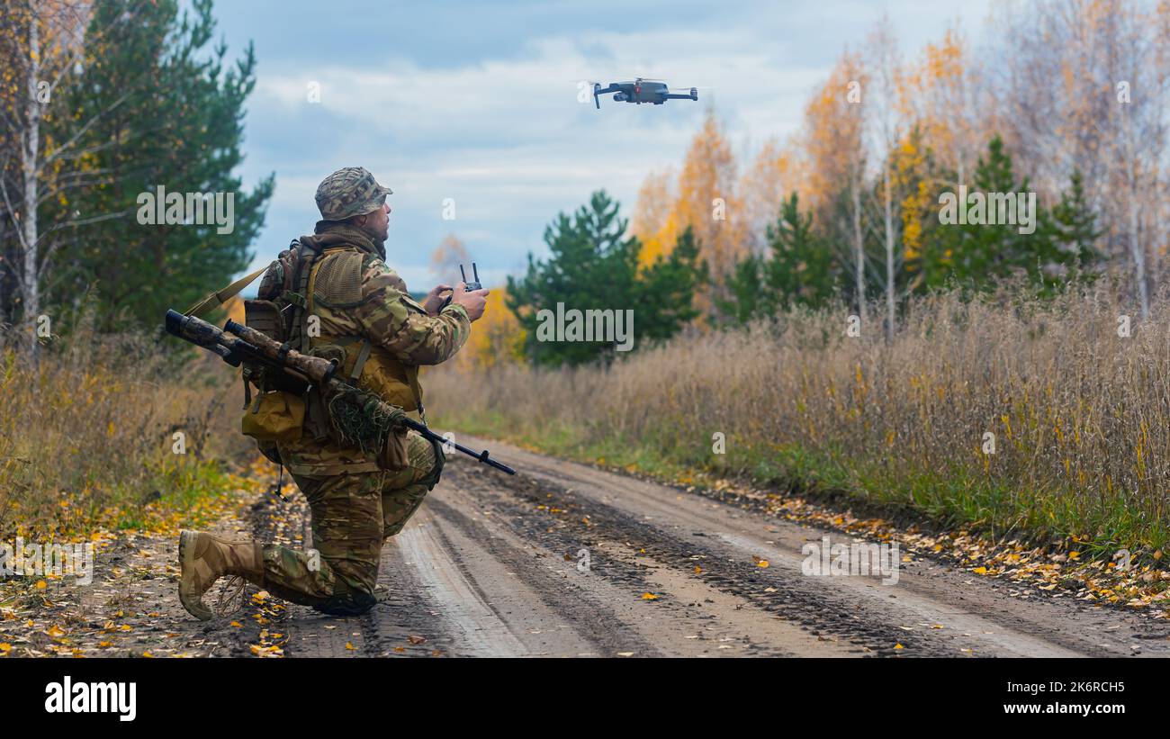 Photo of a mercenary soldier launch a reconnaissance drone on the road in a forest. Modern technological methods of reconnaissance and warfare. Vertic Stock Photo