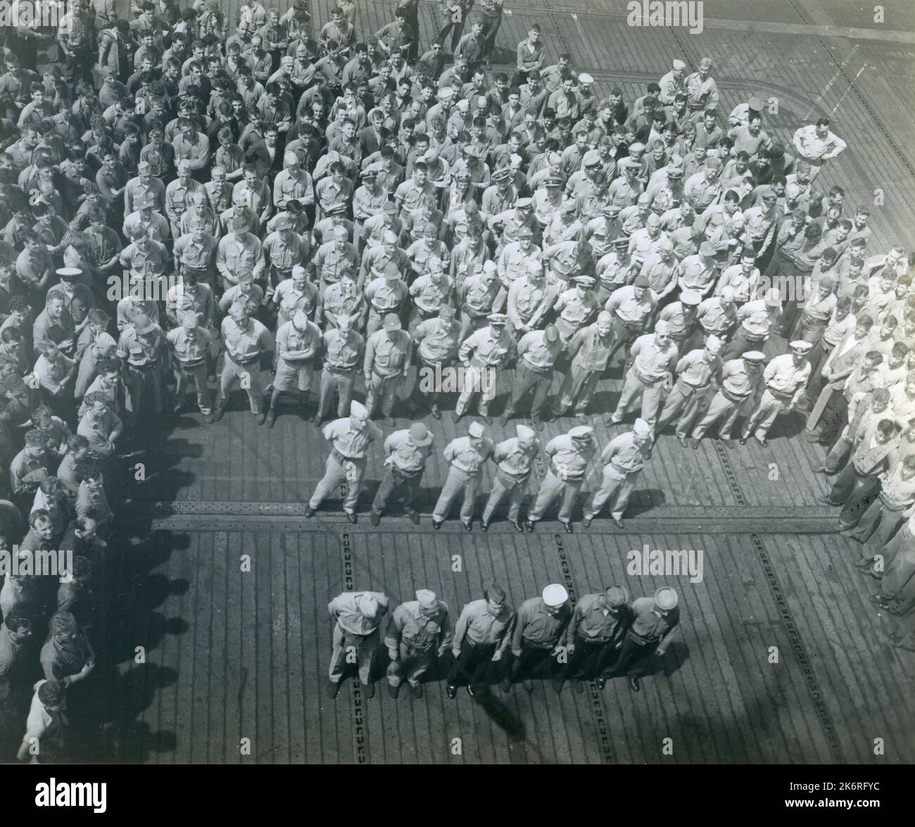 Photograph of a Medal Presentation Ceremony Aboard USS Tulagi'Medal presentation ceremony by the CO Capt. Joseph C. Cronin, USN aboard the USS TULAGI (CVE-72) with all hands assembled on the flight deck. Left to right in front row are: Lt. Ralph K. Andrist and Lt. Edward H. Hudson both Bronze star medals; and Gregory Szellak, ACMM, Gerald A. Donato, AMM2c, Irving R. Miller, AMM2c, Daniel W. Hiller, AEM1c the latter four commendation ribbons.'. Stock Photo