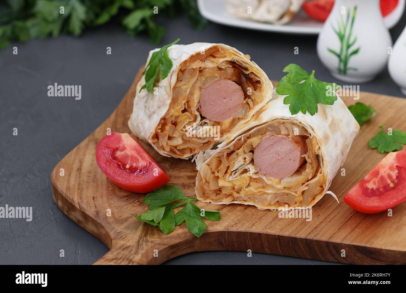 Lavash roll with sausage and stewed cabbage on wooden board Stock Photo