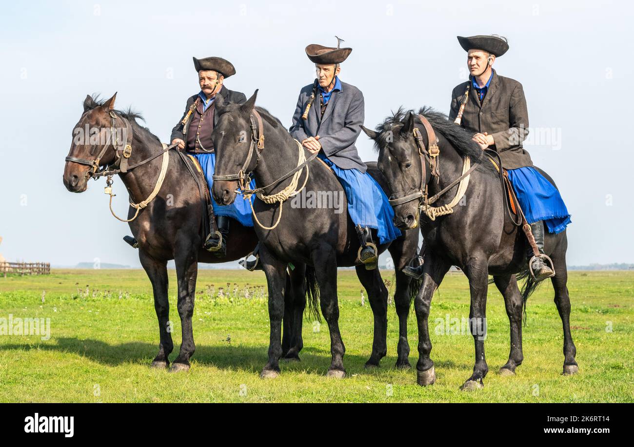 Hortobagy, Hungary – October 15, 2022. Three Hungarian csikosok cowboys on horseback in Hortobagy National Park in Hungary. The csikos is the mounted Stock Photo