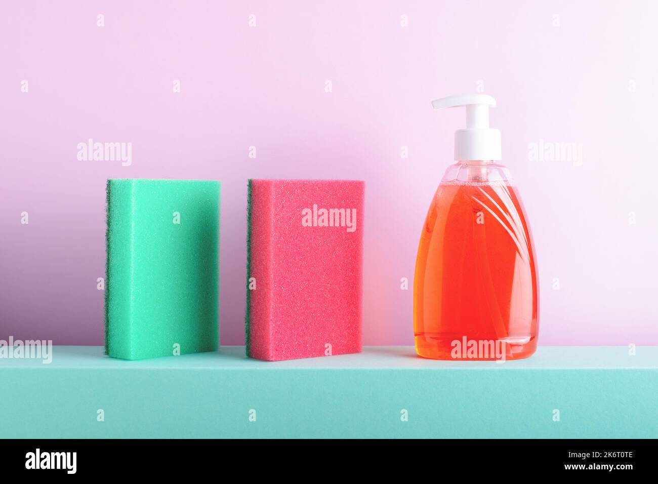 Colourful conceptual still life with kitchen cleaning red and green foam sponges and transparent