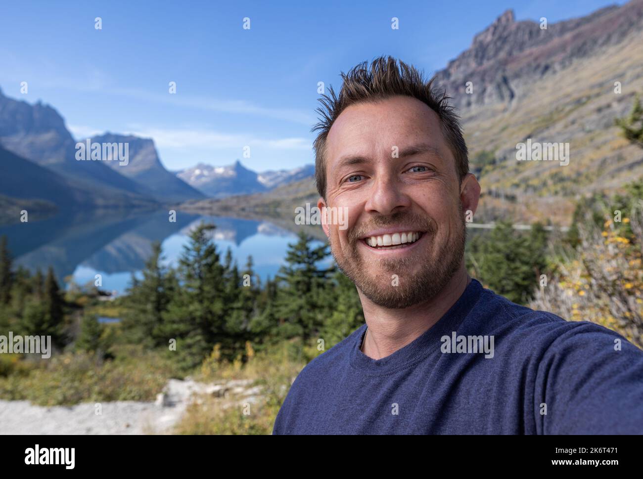 Young man taking a selfie at the St Mary viewpoint in glacier National Park with beautiful calm conditions Stock Photo