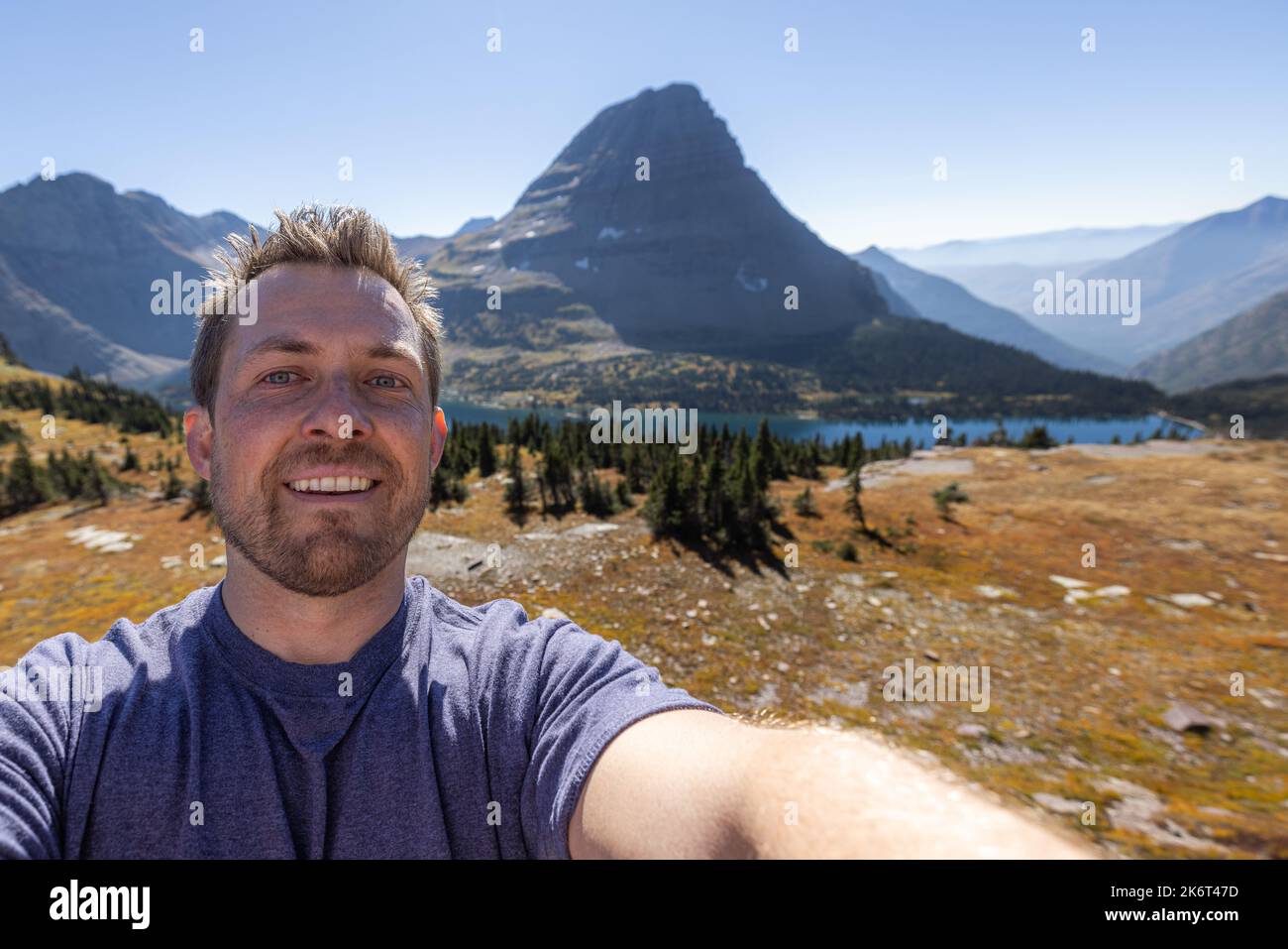 young man taking a selfie with the iconic hidden lake in te background, Glacier National Park. Stock Photo